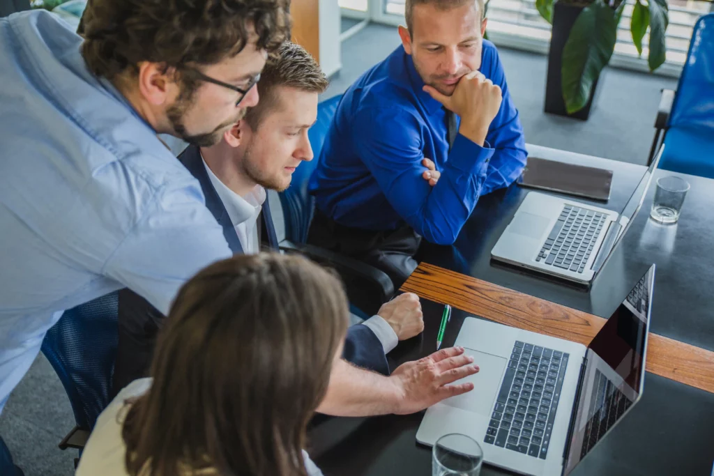 Business team discussing cybersecurity tools and strategies to protect company data on laptops in an office setting.
