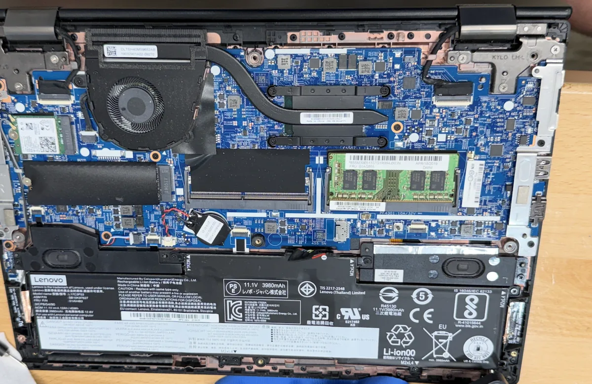 Lenovo laptop opened on the bench showing the RAM slot and M.2 SSD used for upgrades
