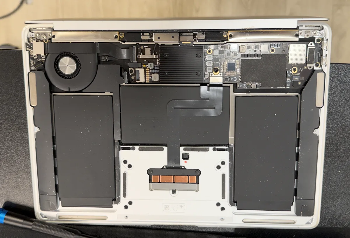 MacBook Air opened for repair on our bench showing the logic board, fan, and battery